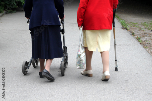 Zwei alte Frauen mit Gehwagen und Stock im Park photo