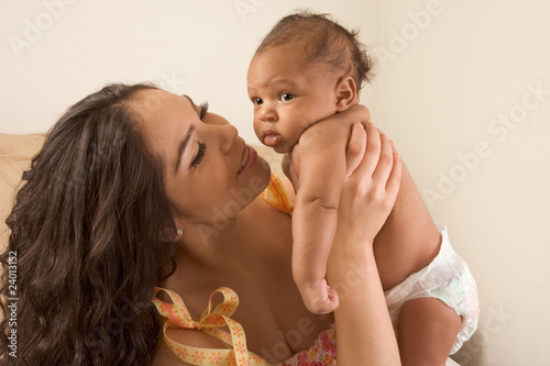 Latina mother playing with her baby boy son on bed