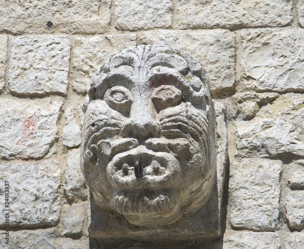 Ancient stone face carved on brickwall.