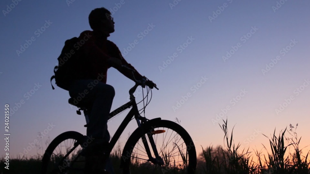 silhouette of man on bicycle stands in field and looks at sky silhouette of man on bicycle stands in field and looks at sky