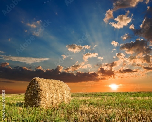 Fototapeta haystack in a field by a sunset