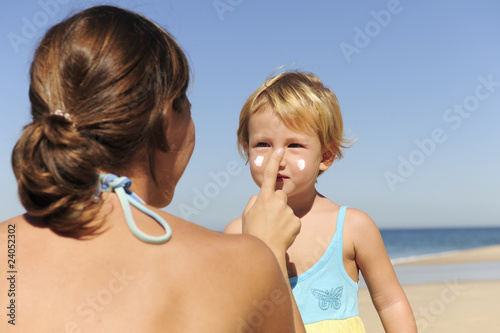 Mother applying sunscream to her daughter