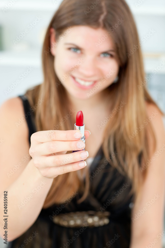 Smiling woman holding lipstick in the camera Smiling woman holding lipstick in the camera