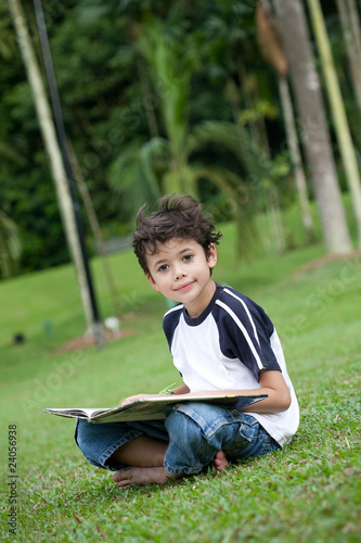 Young boy enjoying his reading book in outdoor park