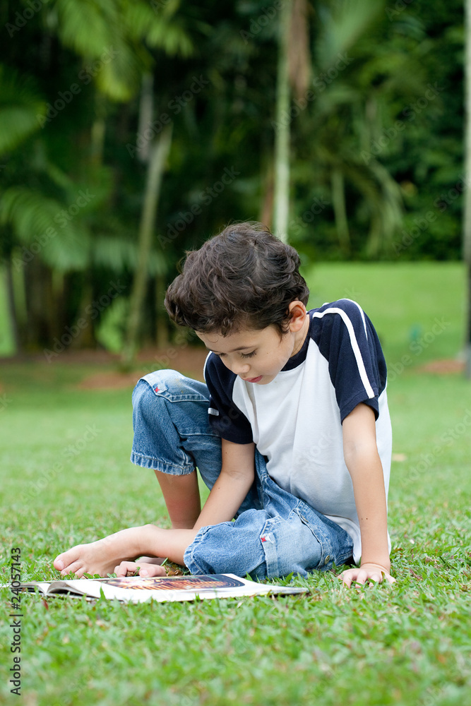 Young boy enjoying his reading book in outdoor park Young boy enjoying his reading book in outdoor park