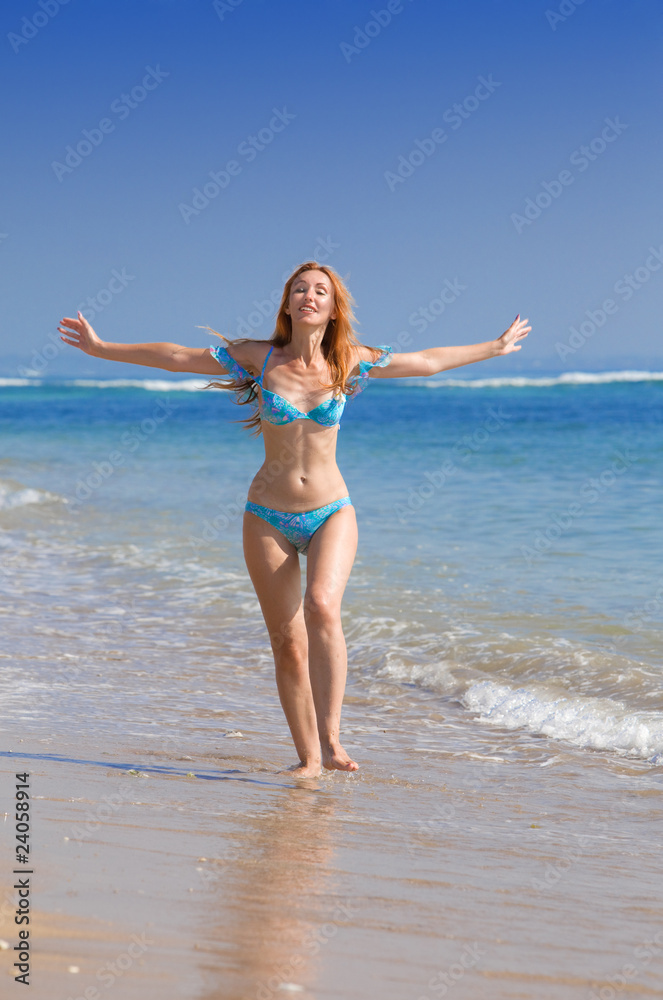 Young graceful woman goes on coast of ocean