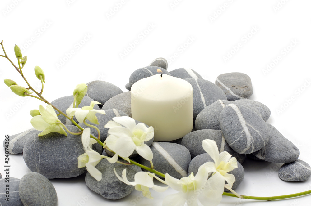 Spa setting with beautiful white flowers, pebbles and candle.
