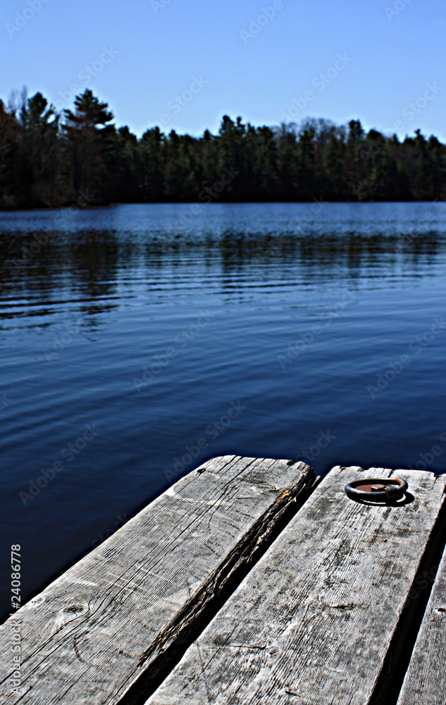 Obraz premium weathered wood dock on serene indigo placid lake in the forest