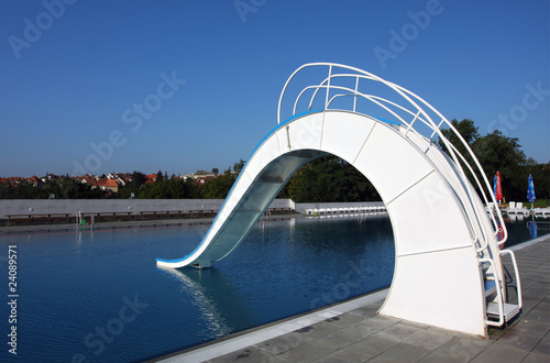 dispeopled bath pool with white slide photo