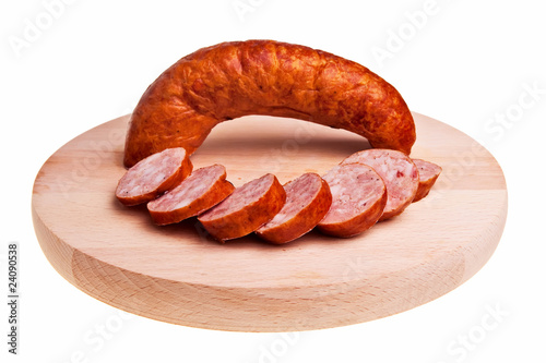 Tasty garlic sausage with few slices over wooden board.