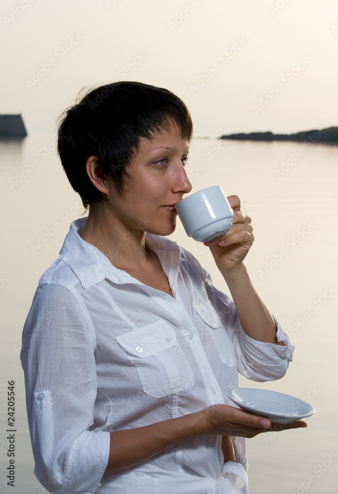 Young woman meets sunrise drinking morning coffee Young woman meets sunrise drinking morning coffee