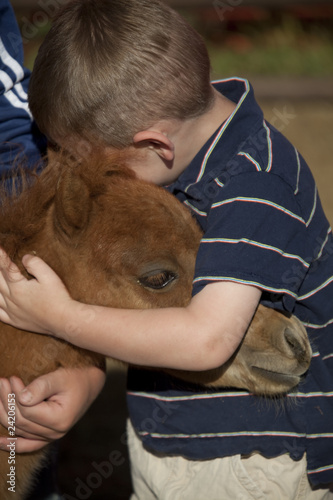 young boy hugging horse