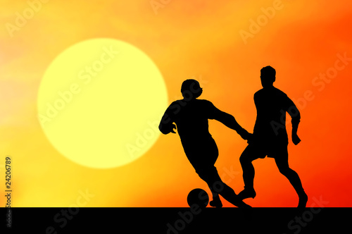 Silhouettes of footballers on the sunset sky