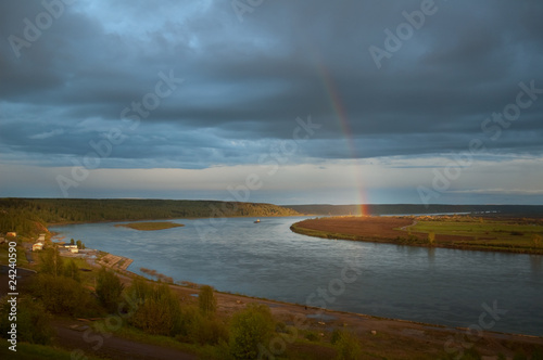 Rainbow on a distant river bank lights all around.