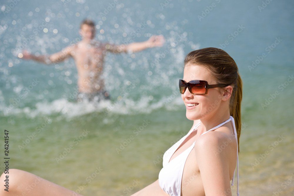 Woman in bikini sunbathing by sea on beach Woman in bikini sunbathing by sea on beach