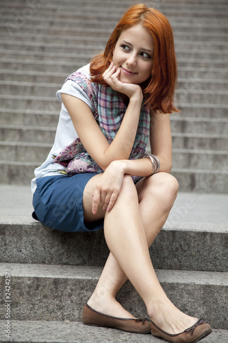 Portrait of beautiful red-haired girl on footstep.