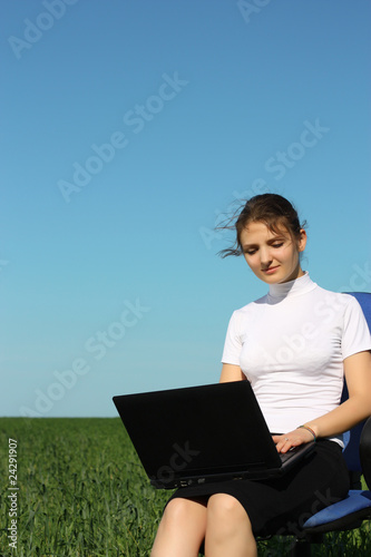 Business woman on a laptop in a field out side the office