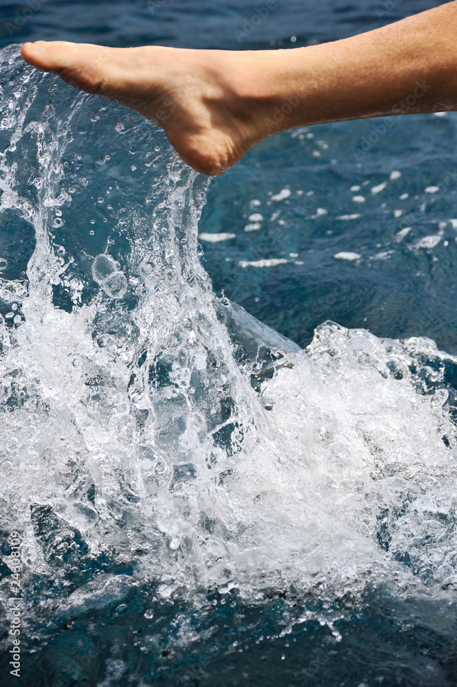 Fototapeta premium Foot of young man in water - splash