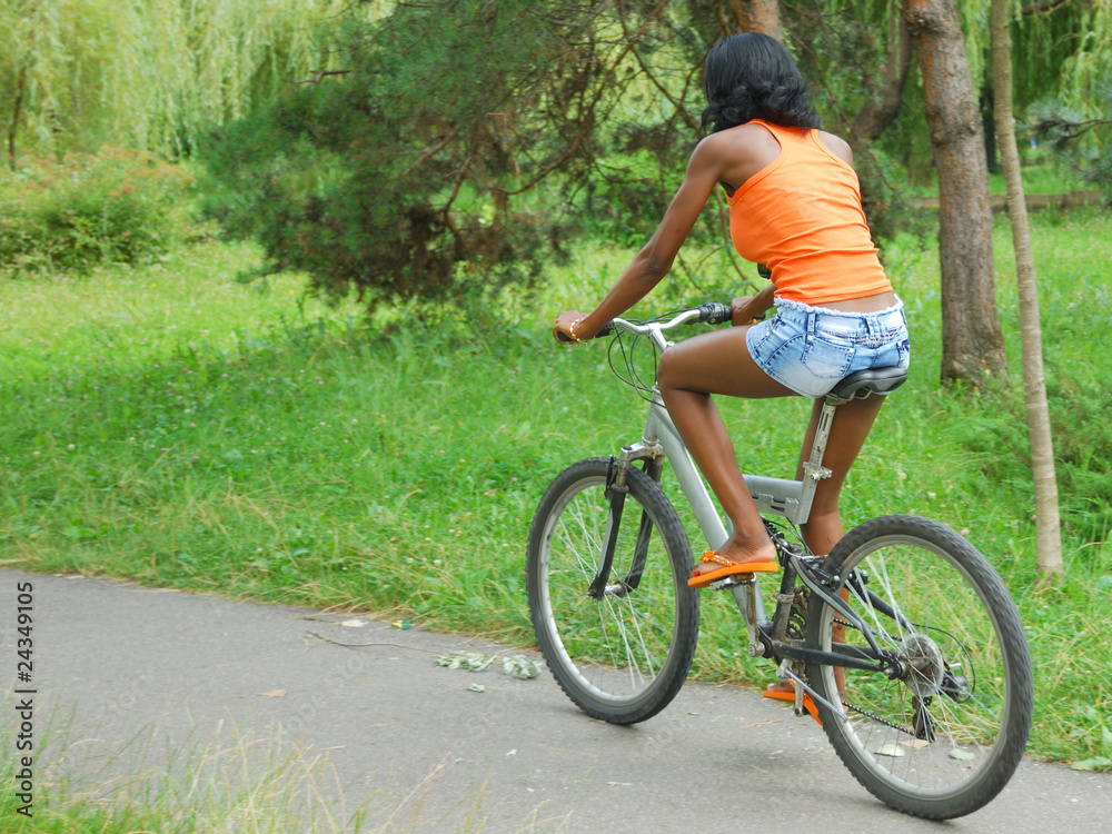 african girl having fun riding a bike in park