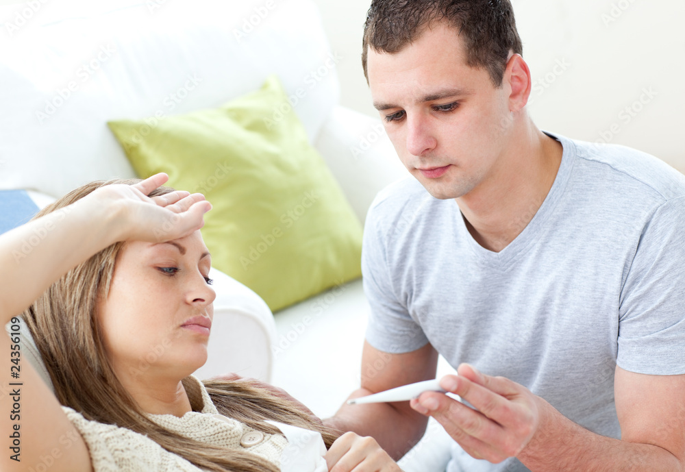 Caring man check the temperature of his sick girlfriend with a t Caring man check the temperature of his sick girlfriend with a t