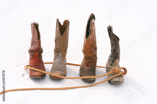 Old roped cowboy boot on sand dune