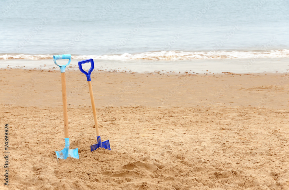 Two children's spades on a sandy beach Two children's spades on a sandy beach