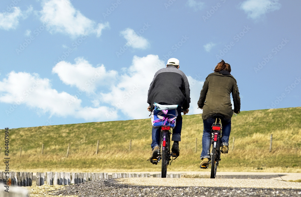 Obraz premium A couple cycling on a causeway in Zeeland