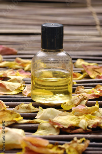 Bottle of essential oil with rose petals