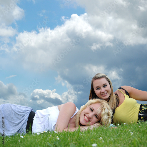 Two girl friends laying in grass