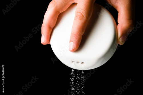 Falling salt from salt shaker on black background