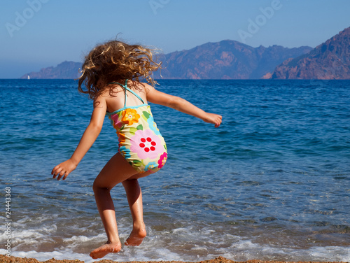 Korsika - Kleines Mädchen hüpft in den Wellen am Strand