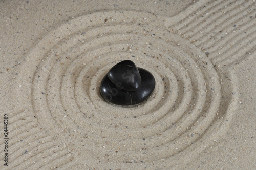 Schwarze Steine Hot Stones im Sand mit Spuren