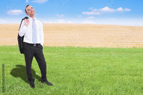 relaxed businessman having break standing in green grass
