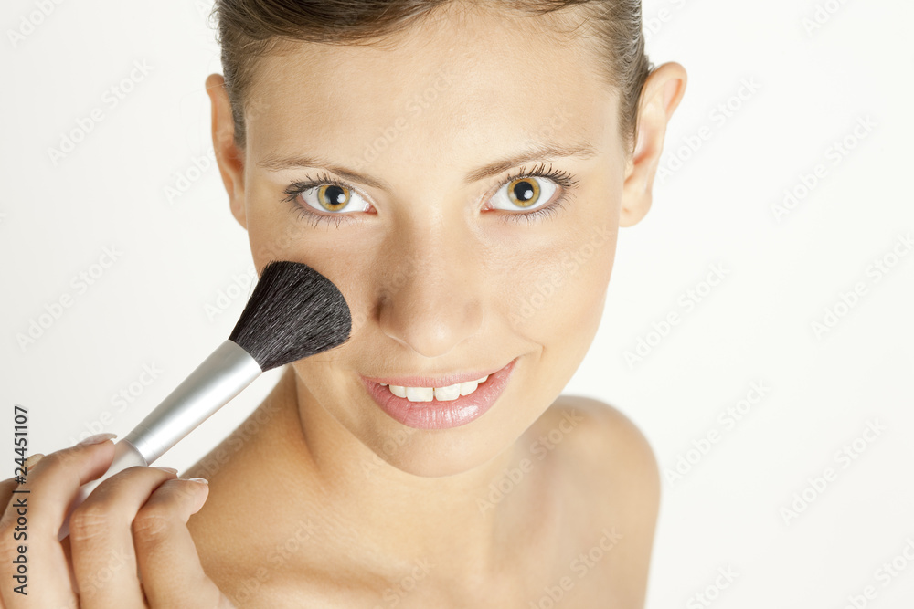 portrait of young woman putting on face powder portrait of young woman putting on face powder