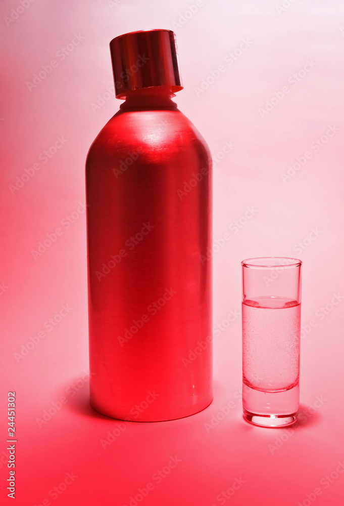 Aluminum bottle and a glass of vodka in pink light Aluminum bottle and a glass of vodka in pink light