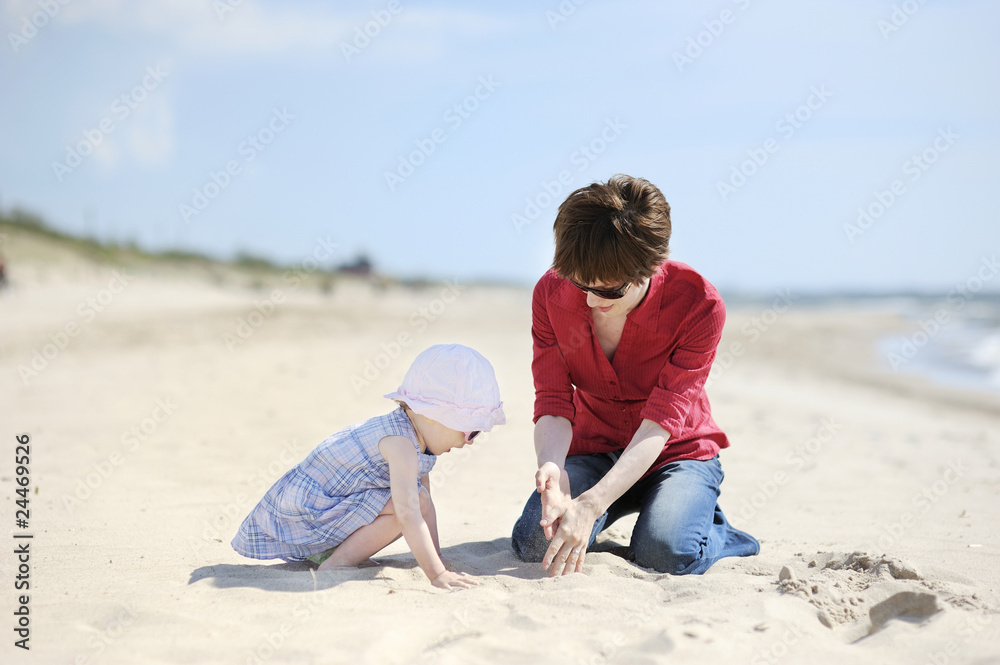 Adorable girl and her mother on a sand beach Adorable girl and her mother on a sand beach