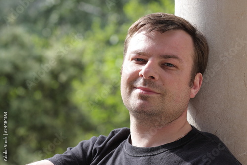 Happy man rests against column