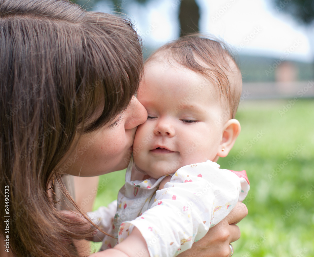 Mom kisses her little daughter, played in the park Mom kisses her little daughter, played in the park