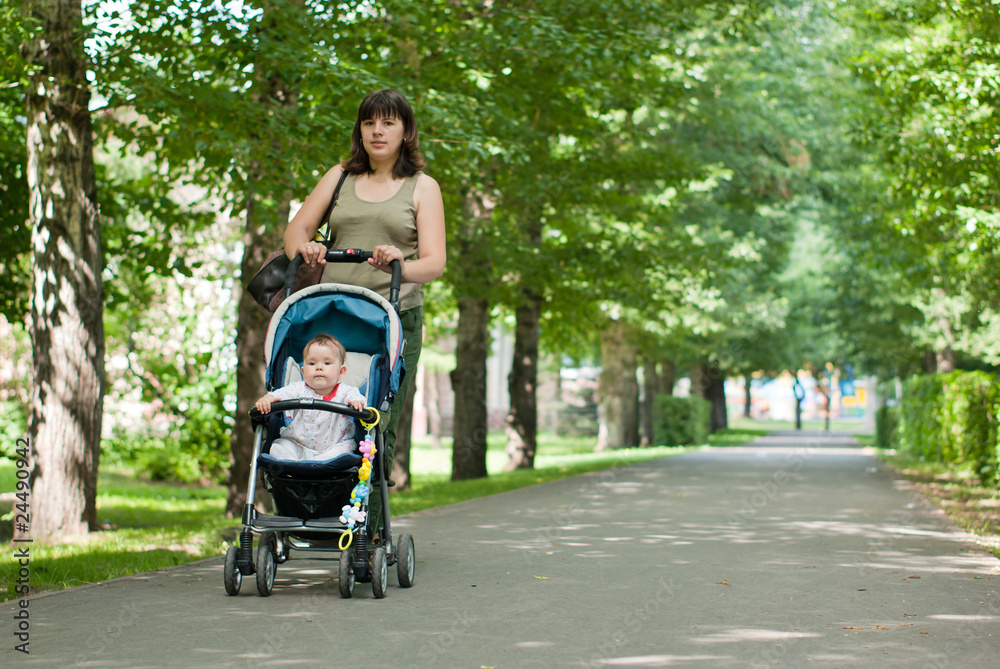 a young mother walking with a baby carriage in the park a young mother walking with a baby carriage in the park