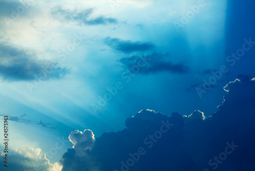 Canvas Print Dramatic clouds and a blue sky with a sunbeam shining through.