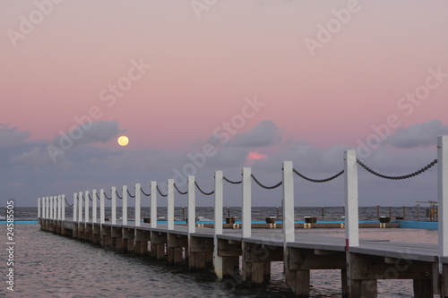 Full moon rising over the ocean at sunset