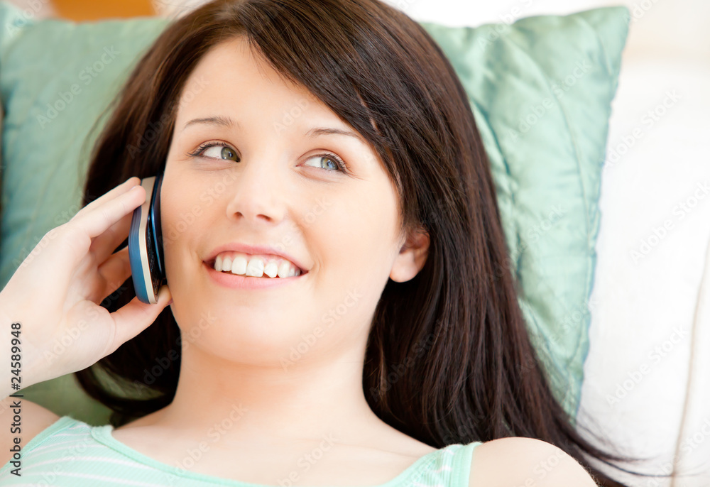 Pretty young woman talking on phone lying on a sofa Pretty young woman talking on phone lying on a sofa