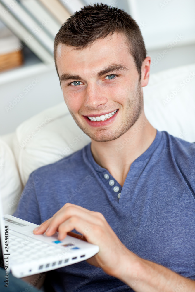 Happy man sitting on the sofa using his laptop Happy man sitting on the sofa using his laptop