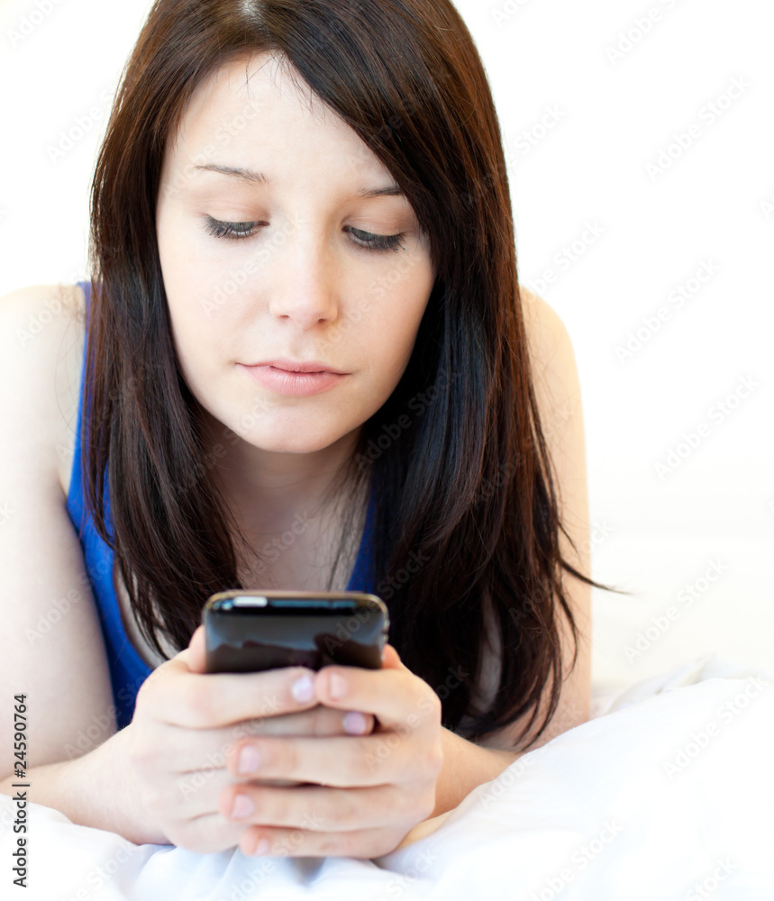 Concentrated young woman texting while lying on a bed Concentrated young woman texting while lying on a bed