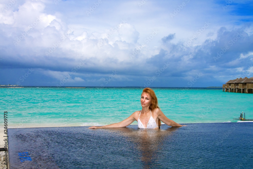 Young pretty woman in the pool and ocean . Maldives..