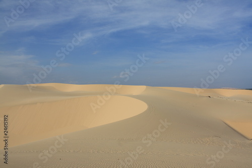 Dünenlandschaft mit weißem Sand vor blauem Himmel