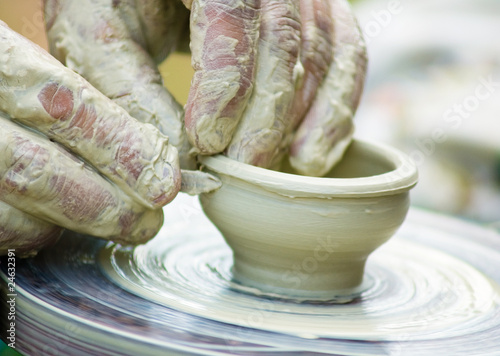 Potters hands creating a clay masterpiece at the turning wheel.