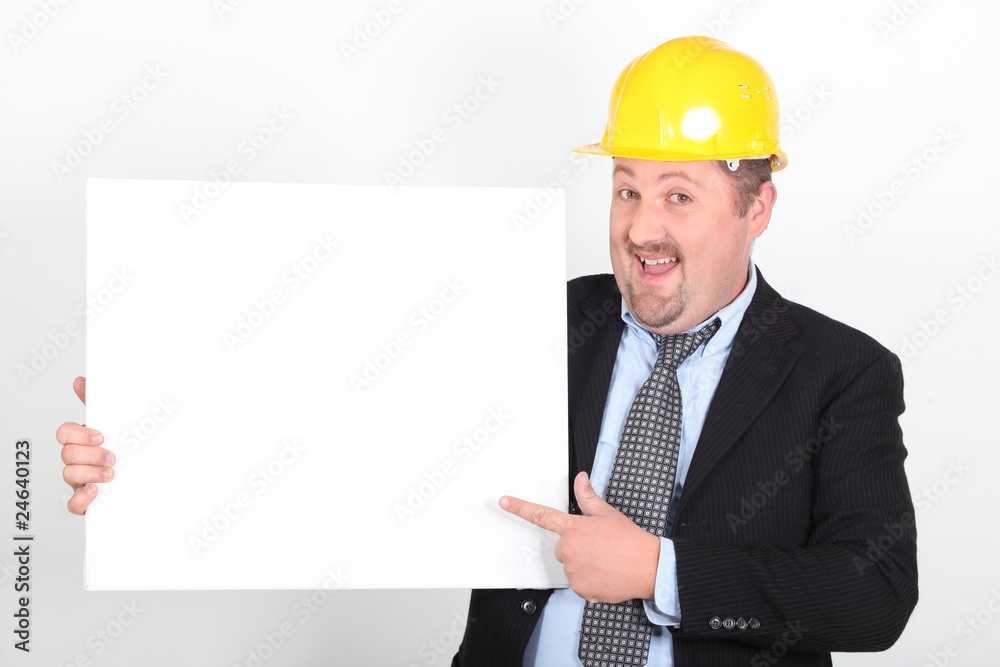 Homme en costume et casque de chantier avec un panneau blanc