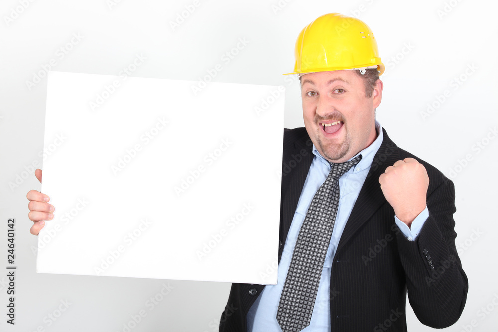 Homme en costume et casque de chantier avec un panneau blanc Homme en costume et casque de chantier avec un panneau blanc