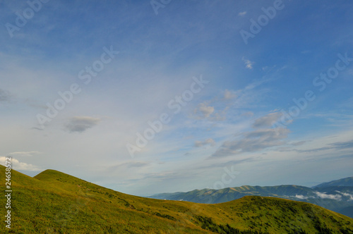 Cloudy blue sky upon green mountains